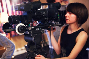 Female student behind camera on set
