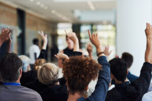 Group with hands up asking questions