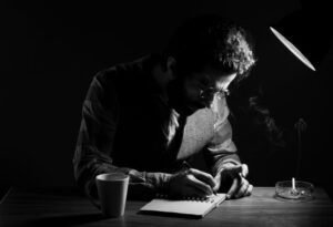 Poet writing under desk lamp