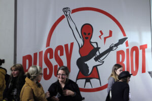 People at event with Pussy Riot banner in background