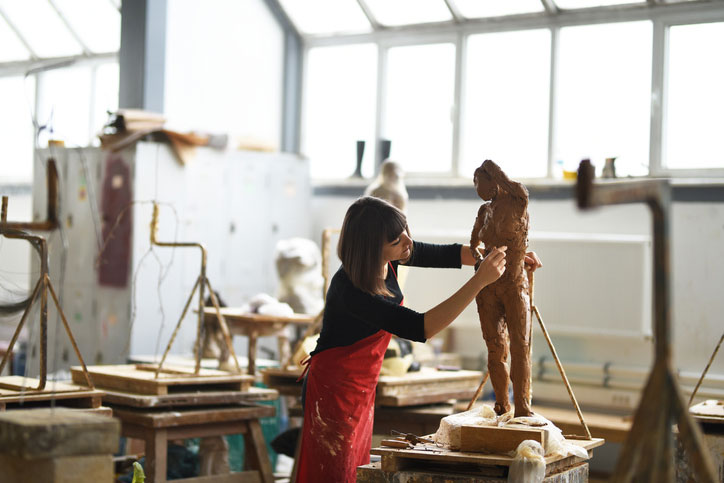 Studio art student sculpting in class