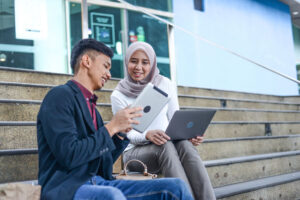 Young business people looking at devices outside