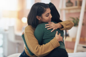 Woman giving supporting embrace to another