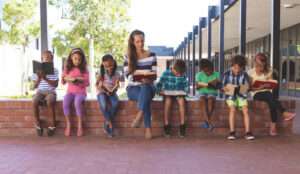 Teacher and young students reading books outside