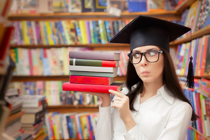 Student with a graduation cap on holding books in one hand and thinking deep